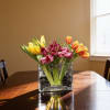 Bright, cheerful tulips arranged in a modern glass vase with decorative black