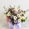 Hughes of purple arrangement in a hat box makes for a beautiful