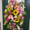 Large standing floral spray with pink, yellow, and peach blooms
