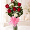 Red roses and white carnations in a glass vase with a pink ribbon