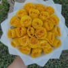 Handheld bouquet of tightly packed yellow roses wrapped in white paper.
