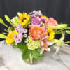Mixed bouquet of roses, lilies, and sunflowers in a glass vase