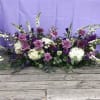 Low floral arrangement with lavender roses, white blooms, and purple accents
