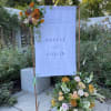Event signage with flower arrangement(s)