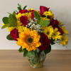Bouquet of red roses and yellow sunflowers in a clear glass vase