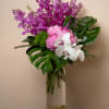 Purple and white orchid bouquet in a tall glass vase