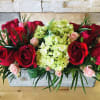 Red roses and pale green hydrangeas in a rectangular wooden box