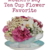 Pink and white flowers arranged in a teacup and saucer