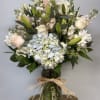A pale blue hydrangea anchors this Soft Serenity Blooms arrangement, surrounded by