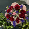 Heart-shaped box of red roses with pink carnations and purple filler flowers
