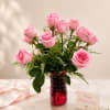 Soft pink roses gathered in a ribbed red glass vase create a