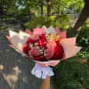 Handheld bouquet of red and pink roses with baby's breath in pink wrapping