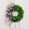 Purple floral wreath on a stand with trailing blooms