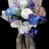 Bouquet of blue, purple, and white flowers wrapped in sheer paper