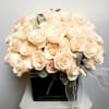 Bouquet of pale peach roses in a black vase with a sheer ribbon