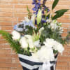 White lilies and carnations in a striped gift box with blue flowers