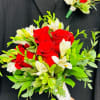 Red roses and white flowers in a hand-tied bouquet with green foliage