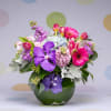 Mixed bouquet of pink, purple, and white flowers in a green vase