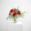 Red roses in a clear glass vase with airy eucalyptus