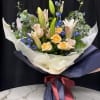 Bouquet of lilies, roses, and blue flowers wrapped in navy paper