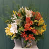 Mixed bouquet of white, yellow, and orange lilies in a decorative vase