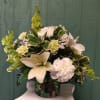 White lilies and carnations in a decorative vase with green foliage