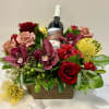 Floral arrangement with roses, orchids, and a wine bottle in a wooden box