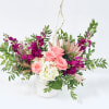 Pink roses and white hydrangea in a white vase with purple flowers