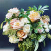 Peach and white roses arranged in a glass vase