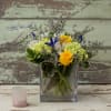 Yellow roses and white flowers in a square glass vase