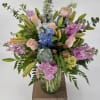 Mixed bouquet in a glass vase with pink roses, lilies, and blue hydrangeas