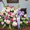 Pink, lavender, and white rose and lily casket spray with a lavender ribbon.