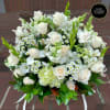 White and cream roses with small white daisies and hydrangea arranged in a basket.