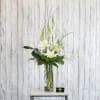 Tall white lily arrangement in a clear glass vase