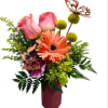 Pink roses and orange gerbera daisies in a burgundy vase with butterfly picks