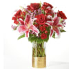 Red roses and pink lilies arranged in a glass vase with a gold base