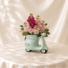 Pink flowers arranged in a mint scooter-shaped vase