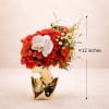 Red rose arrangement in a gold vase with a white orchid accent