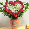 A dense cluster of velvety red roses shaped like a heart makes