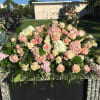 Large pink and white floral arrangement on a stone memorial