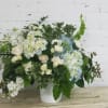 White and pale blue floral arrangement in a white vase