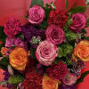 Bouquet of pink, orange, and purple roses with carnations in red wrapping