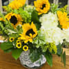 Sunflower and white hydrangea arrangement in a lace-wrapped vase