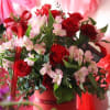 Red roses and pink lilies arranged in a red box with ribbon