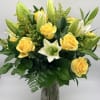 Yellow roses and white lilies in a glass vase