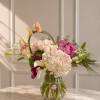 A romantic mix of orchids, roses, hydrangeas, and seasonal blooms in soft
