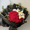 A dense cluster of vivid red roses anchors this premium bouquet, arranged
