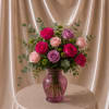 Pink and lavender roses arranged in a purple glass vase