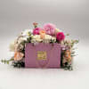 Pink and white flower arrangement in a lavender gift box with a chain handle