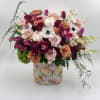 Mixed bouquet of roses, orchids, and tulips in a floral-patterned box